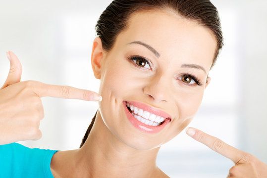 Woman pointing at her straight, white teeth